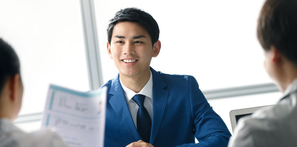A young man in an office attire with a blue gradient background.
