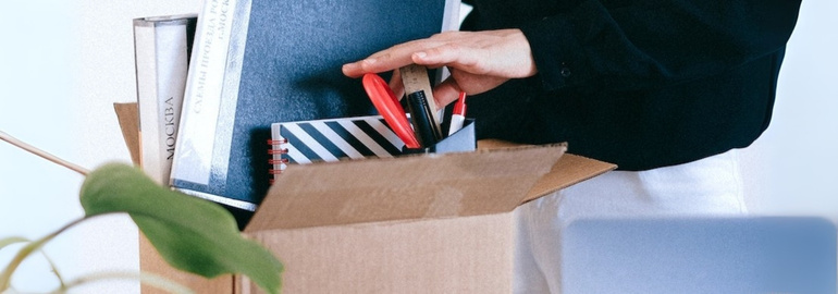 A person unpacks a box with a laptop and a book, representing the transition of changing jobs and preparing for interviews.