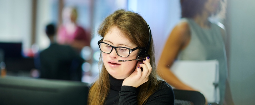 Female professional with Down Syndrome speaking into the mic in the office.