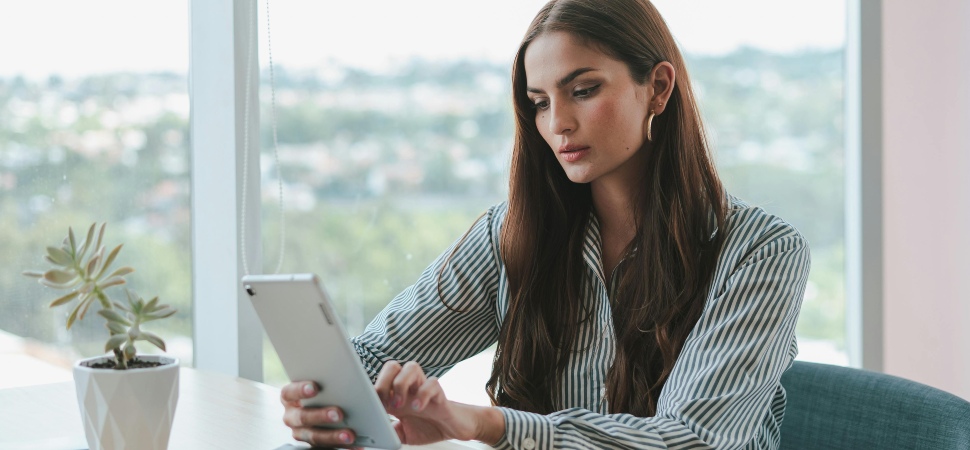 A woman scrolling on her tablet at a desk