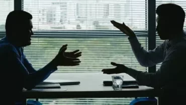 Silhouette of two business professionals engaged in conversation at a table, emphasising collaboration and discussion.