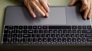 Individual engaged in typing on a laptop, with fingers on the keyboard.