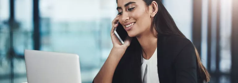 Woman-on-phone-Smiling-While-Using-a-Laptop