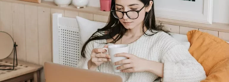 woman sitting on her bed looking at a computer screen