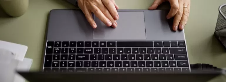 Individual engaged in typing on a laptop, with fingers on the keyboard.